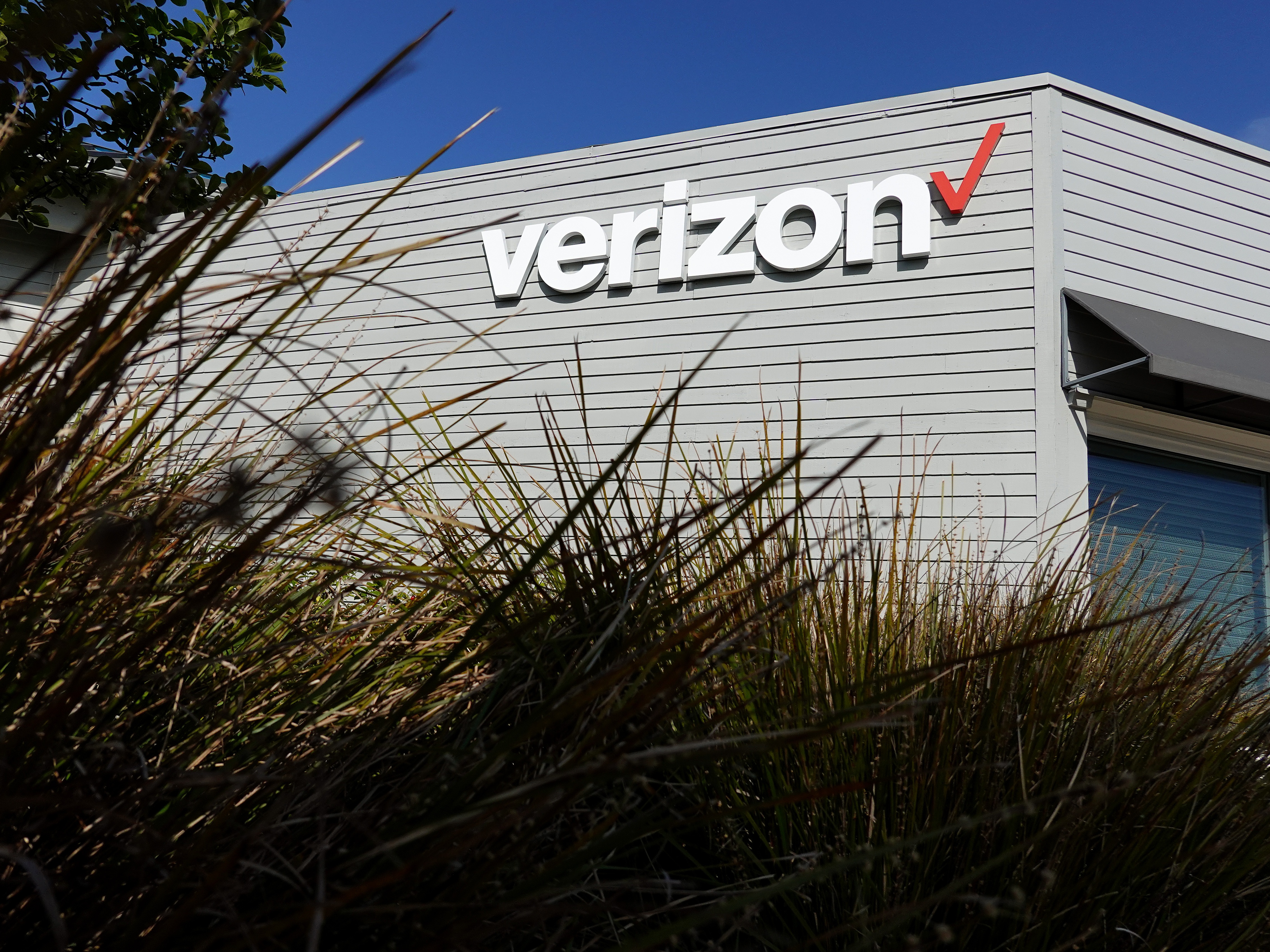 caption: The Verizon logo is displayed on the exterior of a Verizon store. The FCC approved its $20 billion deal to buy Frontier Communications, a day after Verizon told the U.S. regulator that it would end many of its diversity-related policies.