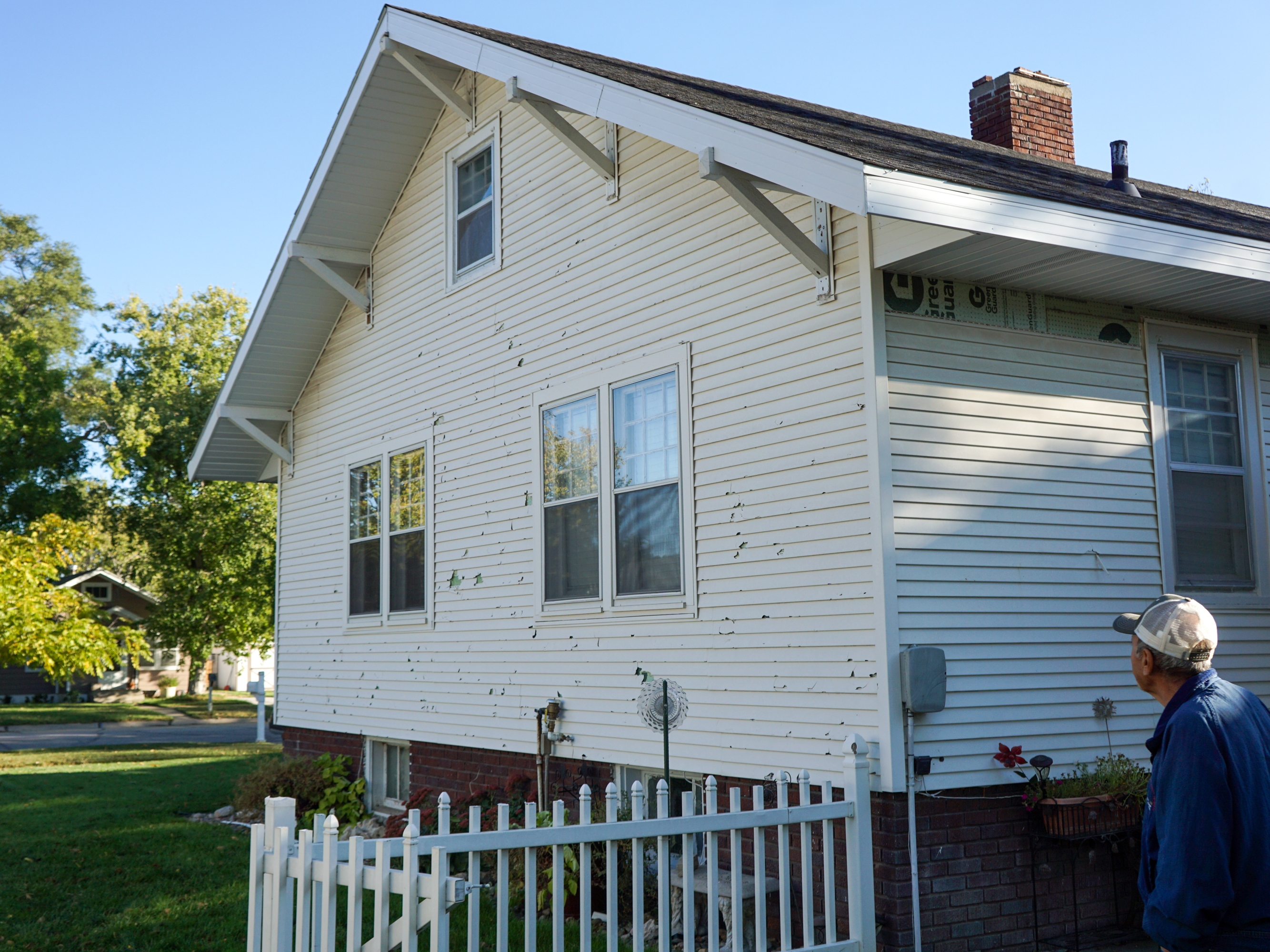 caption: A hailstorm damaged virtually every building in the small town of Cozad, Neb. in June 2024. More than a year later, Baltazar Avalos is still working to fix damage to his home.