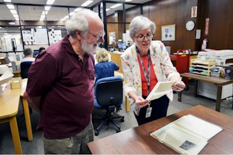 caption: Sue Karren, director of the National Archives in Seattle, shows KUOW listener Ethan Merritt historical photos of the downtown viaduct. June 13, 2019.