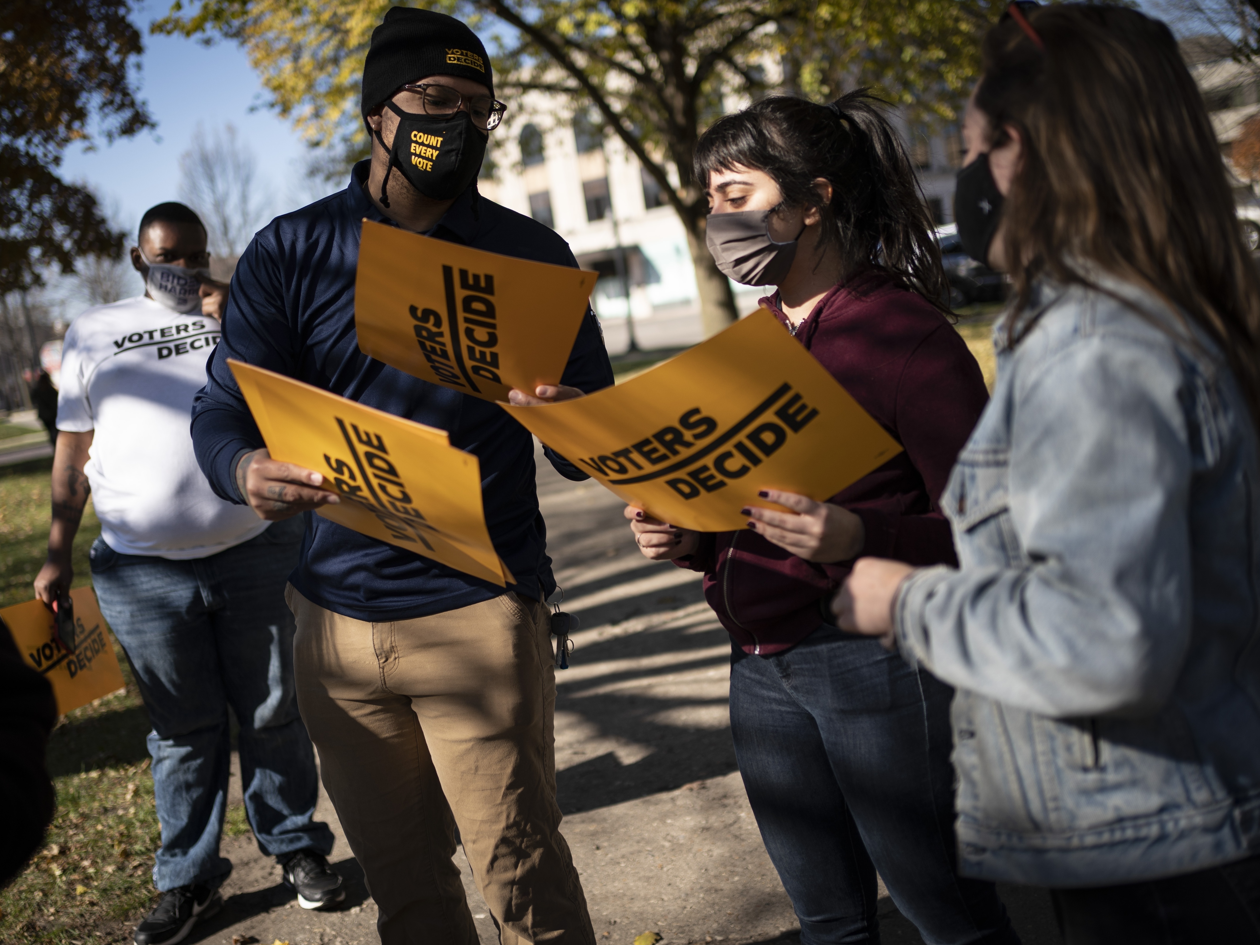 caption: People gather with signs that read "Voters Decide" at the Civic Center Park while waiting for the results of election in Kenosha, Wis., on Wednesday.