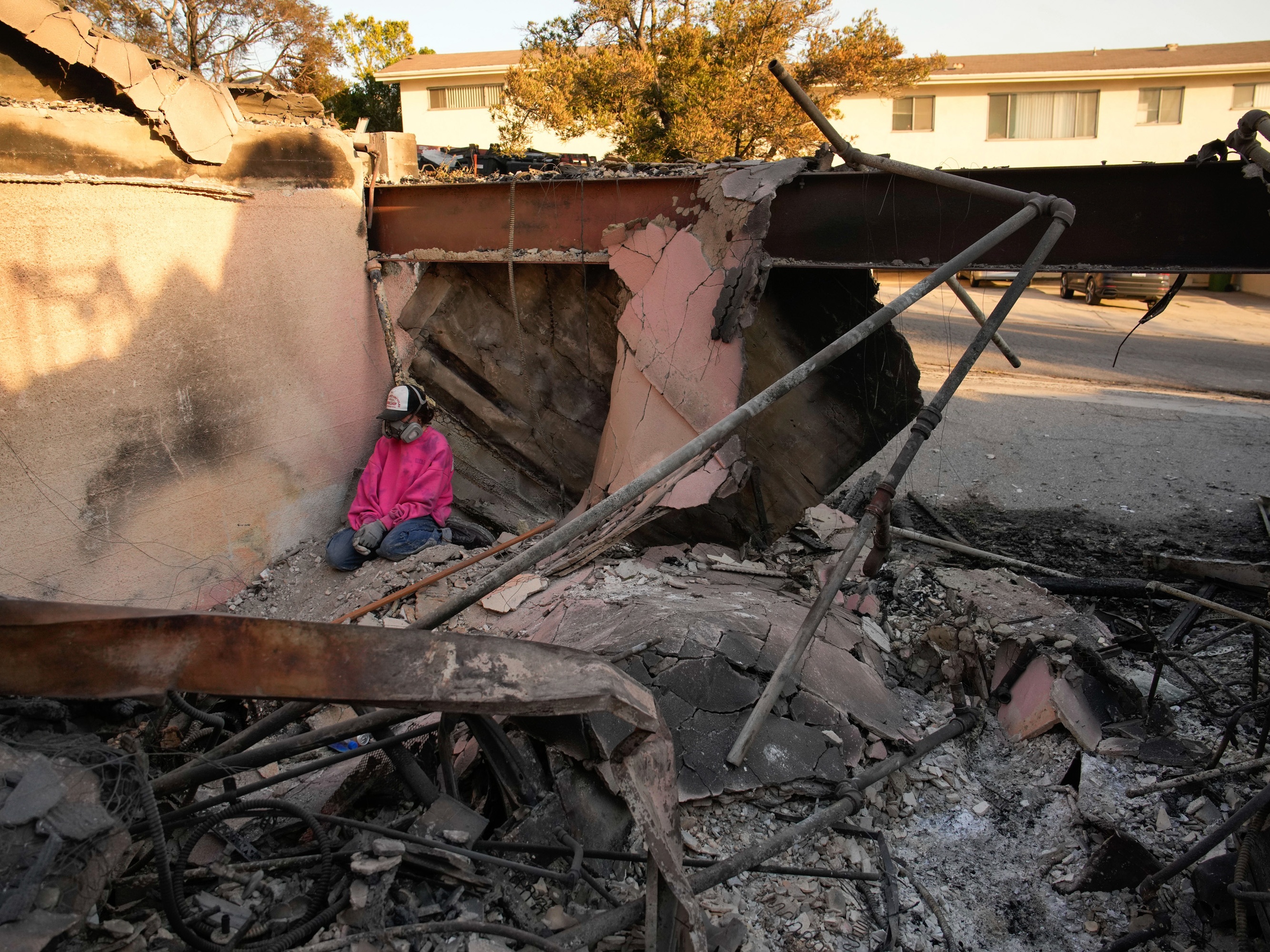 caption: Saturday, Jan. 11: Kaegan Baron sits amid the rubble of her mother's home, which was destroyed by the Palisades Fire in the Pacific Palisades neighborhood of Los Angeles.