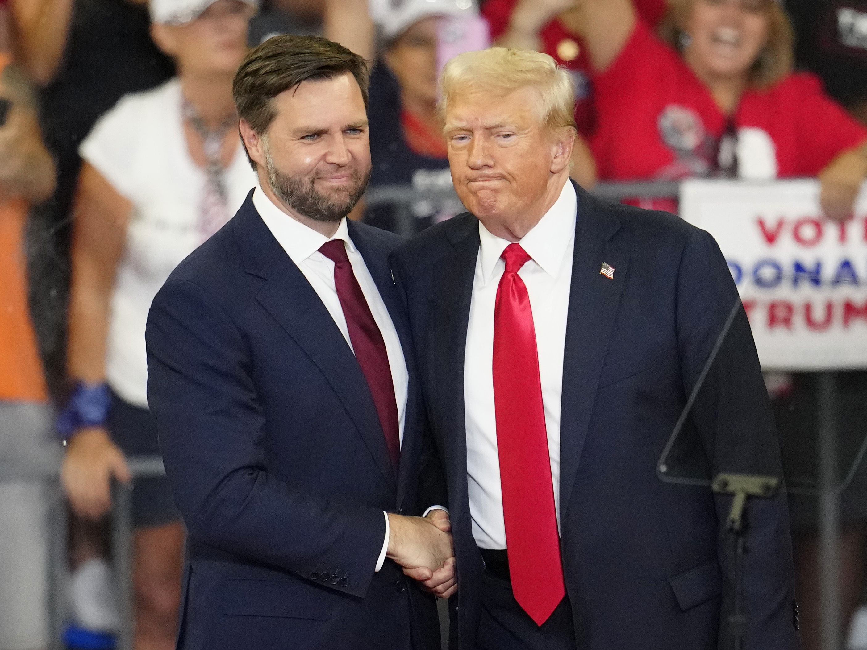 caption: Former President Trump and his running mate, Sen. JD Vance of Ohio, shake hands at a campaign rally at Georgia State University in Atlanta, on Aug. 3, 2024. 