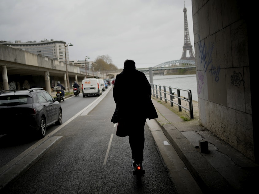 caption: A man rides a scooter in Paris, on March 31. The city has now banned rental electric scooters.