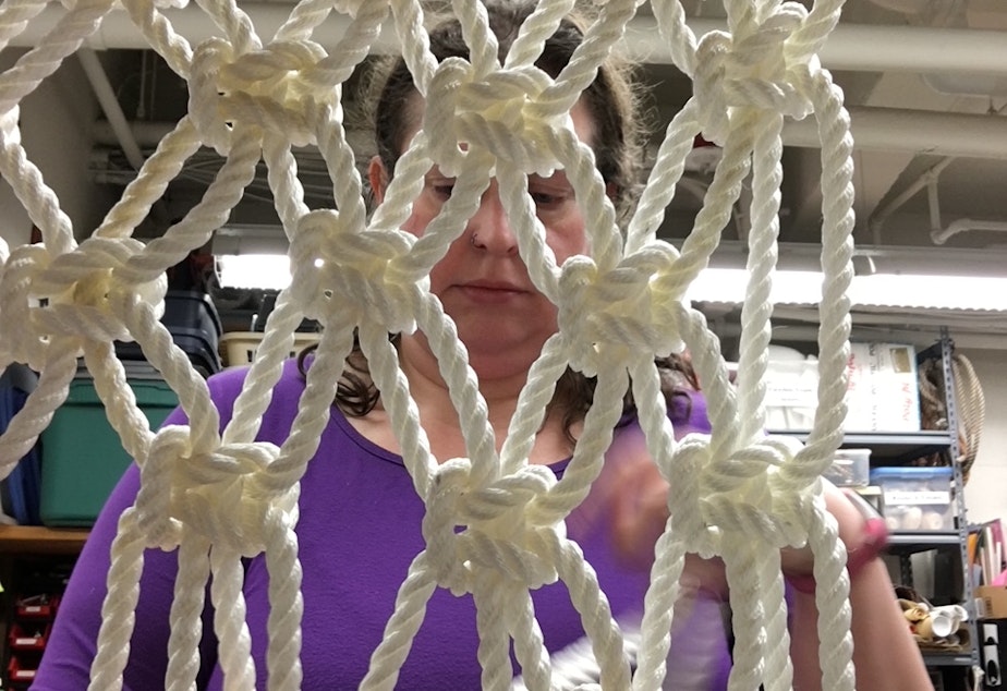 caption: Tristan Hansen, the 5th Avenue Theatre props master, works on macrame set pieces for a production of "Mamma Mia."