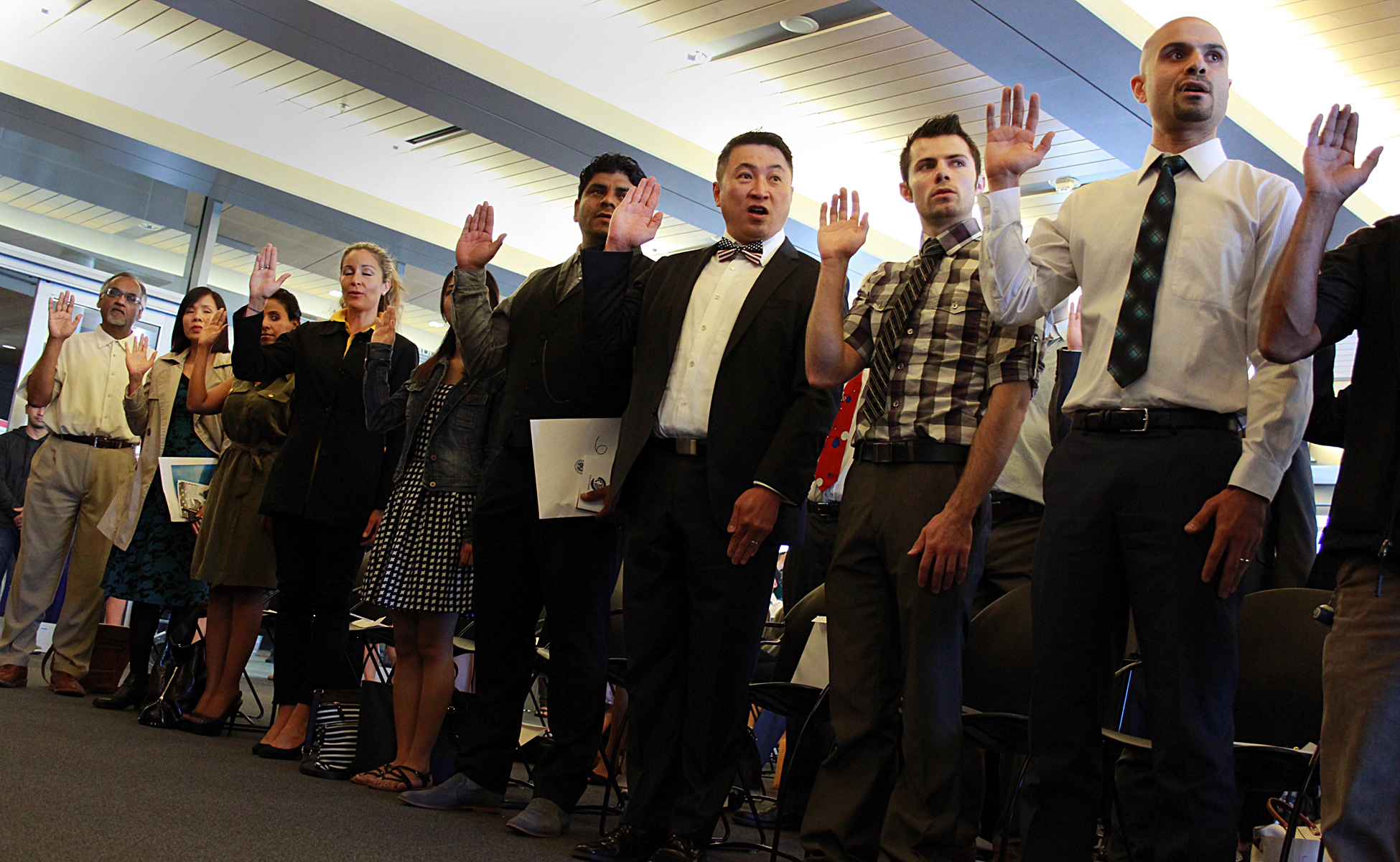 caption: New American citizens take the oath at Seattle City Hall on Flag Day on Sunday.