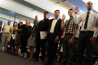 caption: New American citizens take the oath at Seattle City Hall on Flag Day on Sunday.