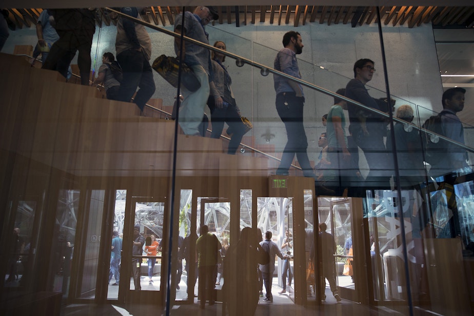caption: Amazon employees and their parents are reflected leaving the Day 1 Building during Amazon's bring your parents to work day on Friday, September 15, 2017, in Seattle. 