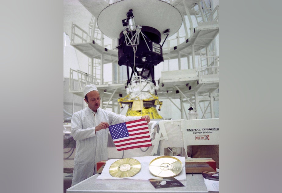 caption: As NASA's two Voyager spacecraft travel out into deep space, they carry a small American flag and a Golden Record packed with pictures and sounds -- mementos of our home planet. This picture shows John Casani, Voyager project manager in 1977, holding a sm