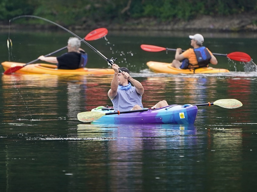 caption: A fisherman in a kayak makes a cast on Lake Arthur at Moraine State Park in Portersville, Pa. Sales of camping, outdoor and recreational equipment have been surging.