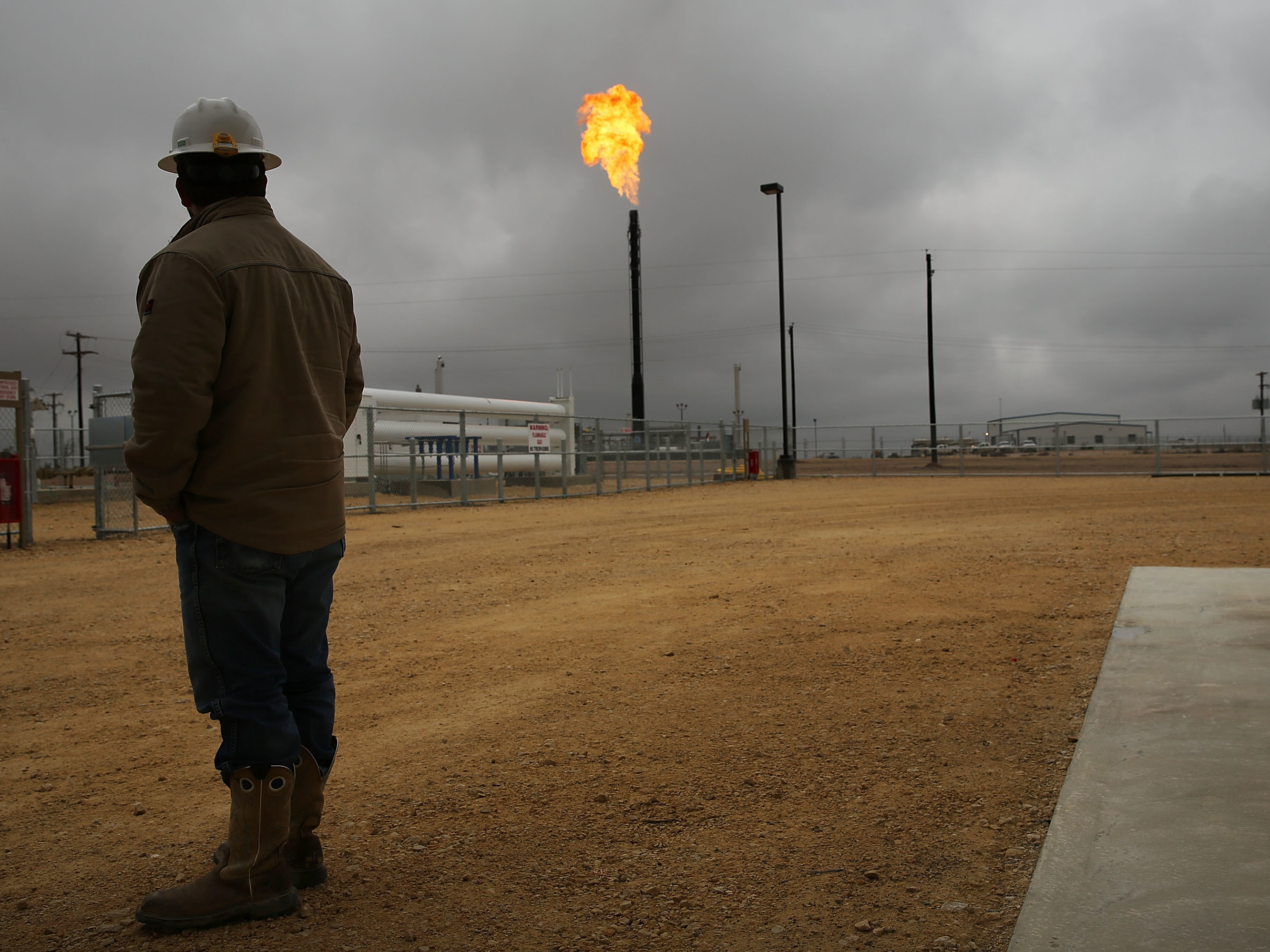 caption: Flared natural gas is burned off at Apache Corporations operations at the Deadwood natural gas plant in the Permian Basin on February 5, 2015 in Garden City, Texas.