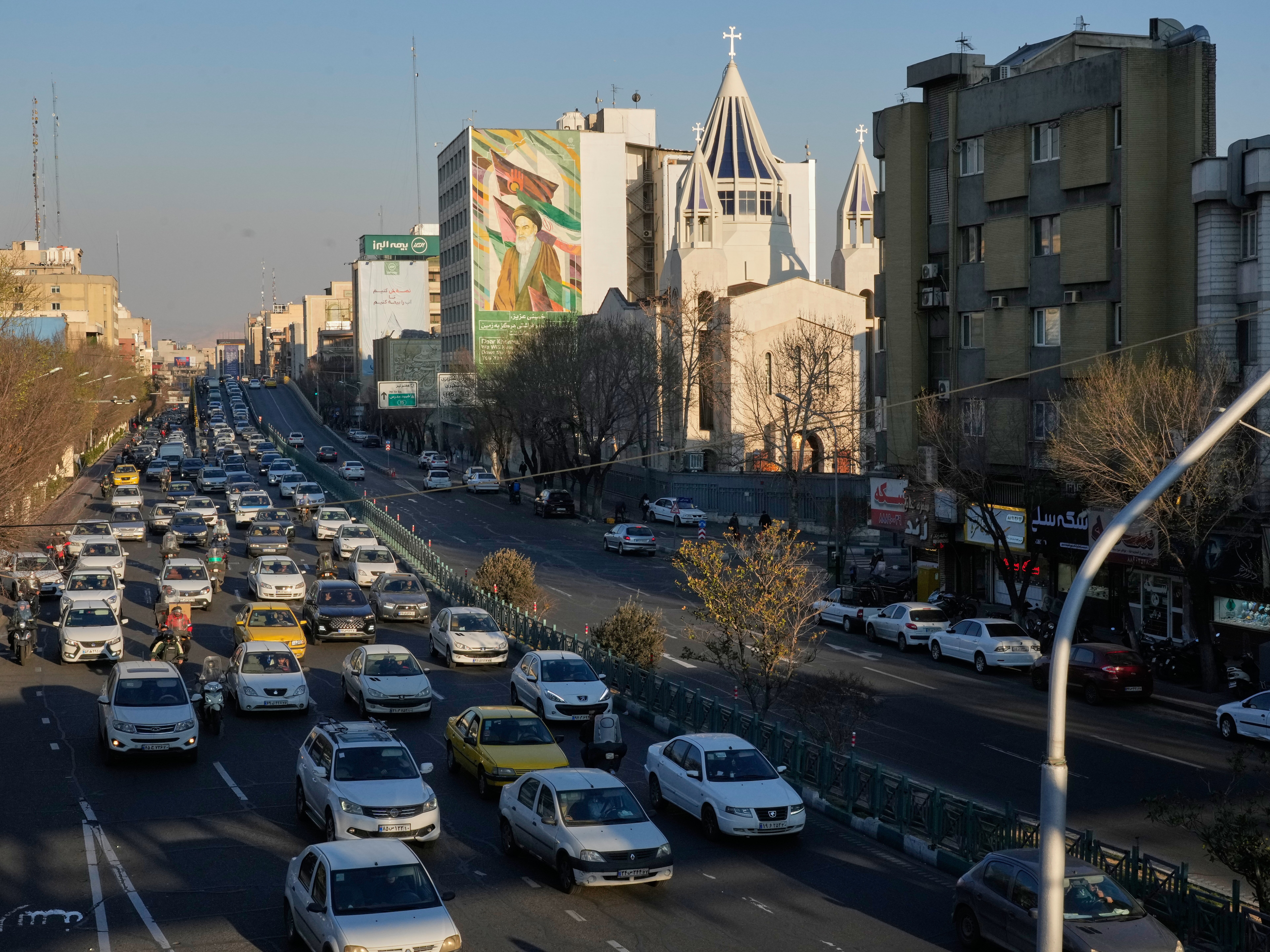caption: Vehicles drive past the Saint Sarkis church and a painting of the late Iranian revolutionary founder Ayatollah Khomeini in downtown Tehran, Iran, Wednesday, Feb. 25, 2026.