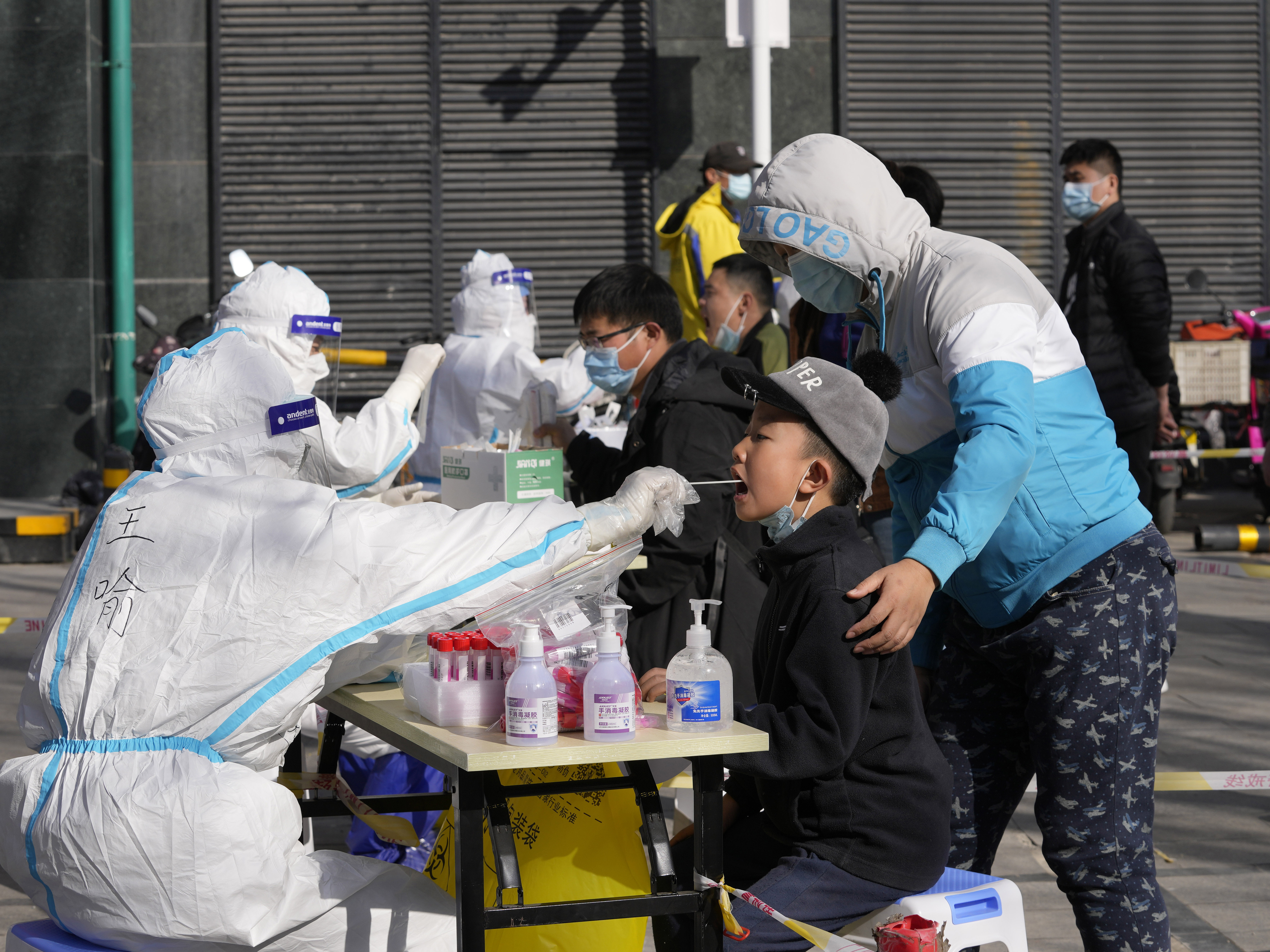 caption: Residents get tested for the coronavirus at an outdoor facility on Monday in Beijing.