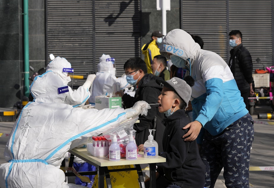 caption: Residents get tested for the coronavirus at an outdoor facility on Monday in Beijing.