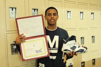 caption: RadioActive youth reporter Mohamed Mohamed is a self-described sneakerhead. Here he poses with his RadioActive workshop diploma and one of his pairs of kicks.