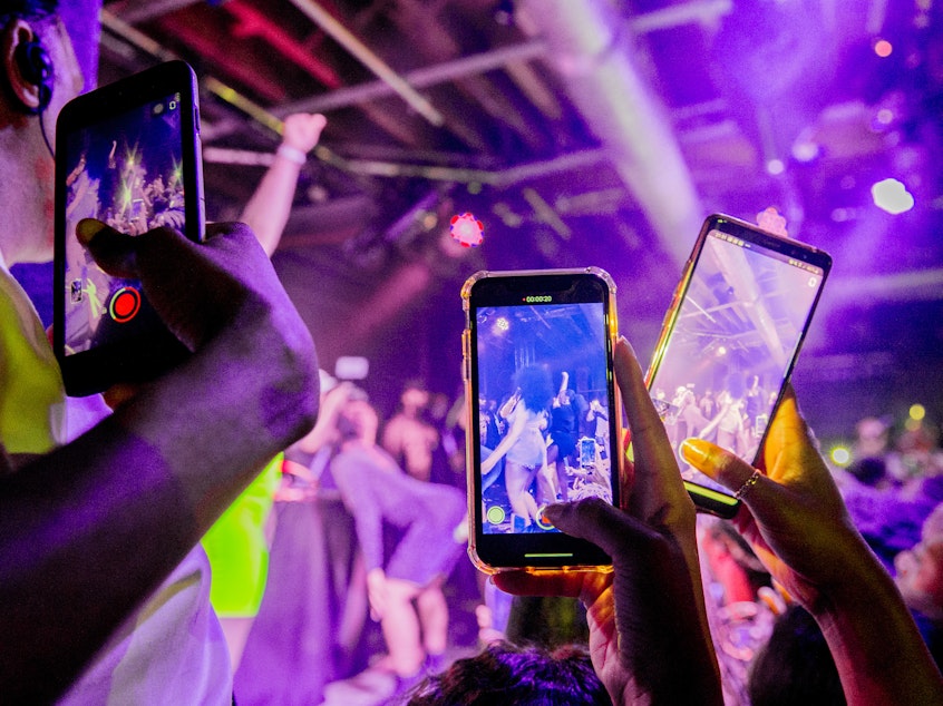 caption: You can do a lot of things with minimal risk after being vaccinated. Although our public health expert says that maybe it's not quite time for a rave or other tightly packed events. Above: Fans take photographs of Megan Thee Stallion at a London show in 2019.