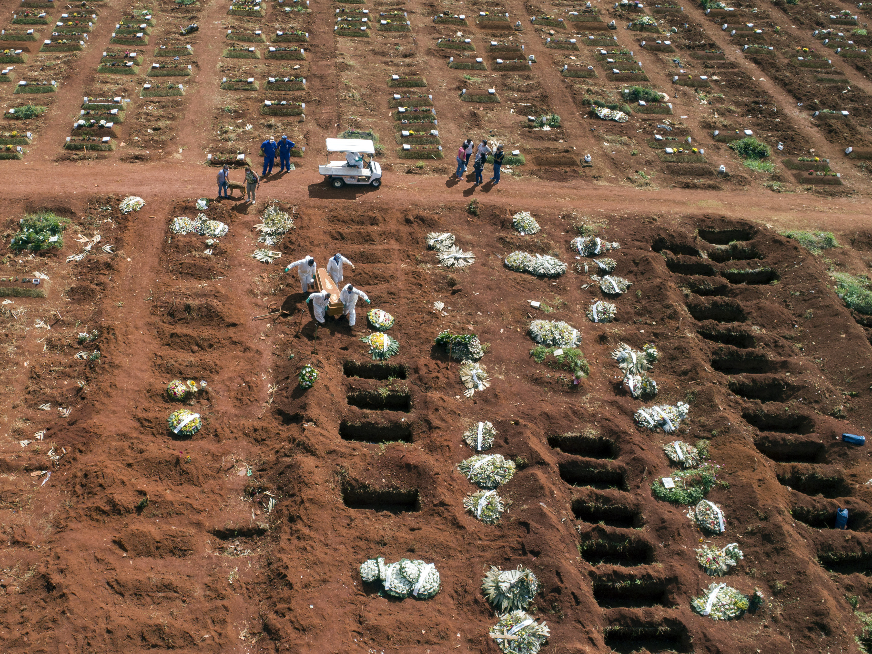 caption: Cemetery workers wearing protective gear carry the coffin of a person who died from complications related to COVID-19 to a gravesite at the Vila Formosa cemetery in Sao Paulo, Brazil, Wednesday, April 7, 2021.