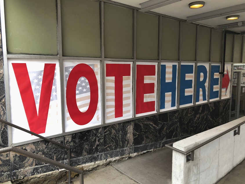 caption: A "Vote Here" sign marks the entrance to an early voting station in downtown Minneapolis in 2018.