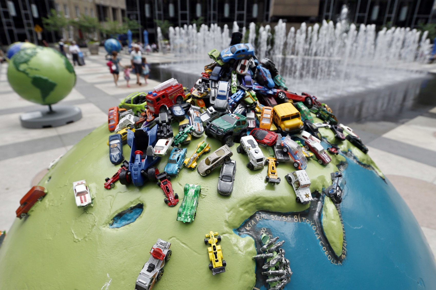 caption: People walk through public art, including one called "Carpool", from the part of the Cool Globes exhibit surrounding the fountains in PPG Plaza on Thursday, June 21, 2018, in Pittsburgh. (Keith Srakocic/AP)