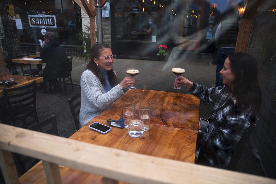 caption: Shelby Klemmt, left, and Lexi Newell cheers while dining at Gracia on Monday, March 22, 2021, on Ballard Avenue Northwest in Seattle. Beginning Monday, restaurants, retailers, and fitness centers can open with up to 50% capacity as Washington's 39 counties move into the third phase of Gov. Jay Inslee's reopening plan. 