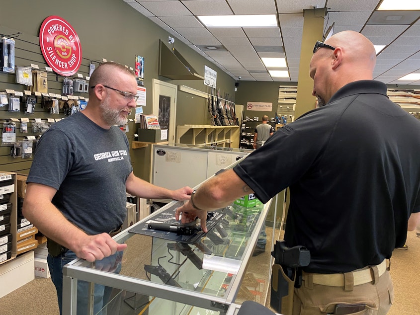 caption: "Most of it is is new gun owners," says Michael Weeks (left), a gun store owner in Gainesville, Ga. By one estimate, Americans have bought nearly 3 million more guns than usual since March.