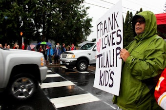 caption: Frank Rivas, a former custodian at Tulalip Elementary, shows his support as Marysville-Pilchuck High School students returned to school following a shooting on October 24, 2014.