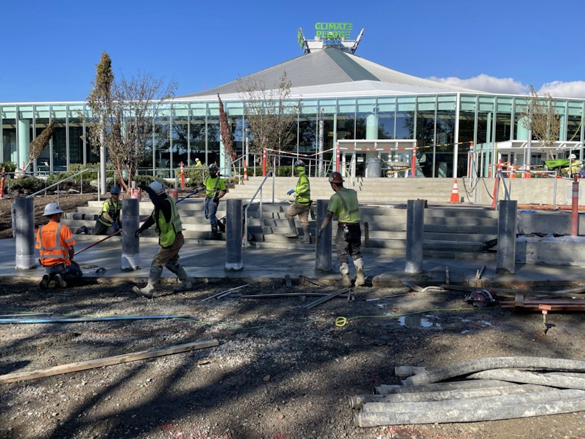 caption: Workers finish concrete and plant landscaping around Climate Pledge Arena on Friday, October 8, 2021.