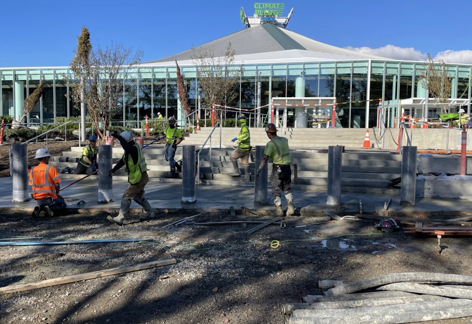 caption: Workers finish concrete and plant landscaping around Climate Pledge Arena on Friday, October 8, 2021.