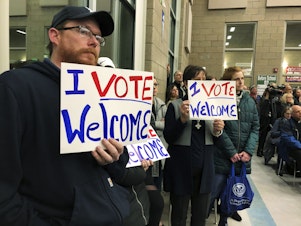caption: In this Dec. 9. 2019, file photo, residents in support of continued refugee resettlement hold signs at a meeting in Bismarck, N.D.