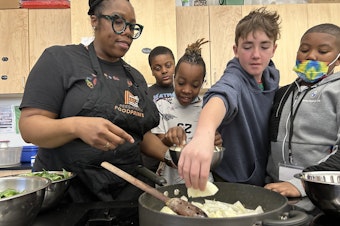 caption: Students help instructional coach Regina Green caramelize onions for a dish featuring fresh greens from the school garden at Watkins Elementary.