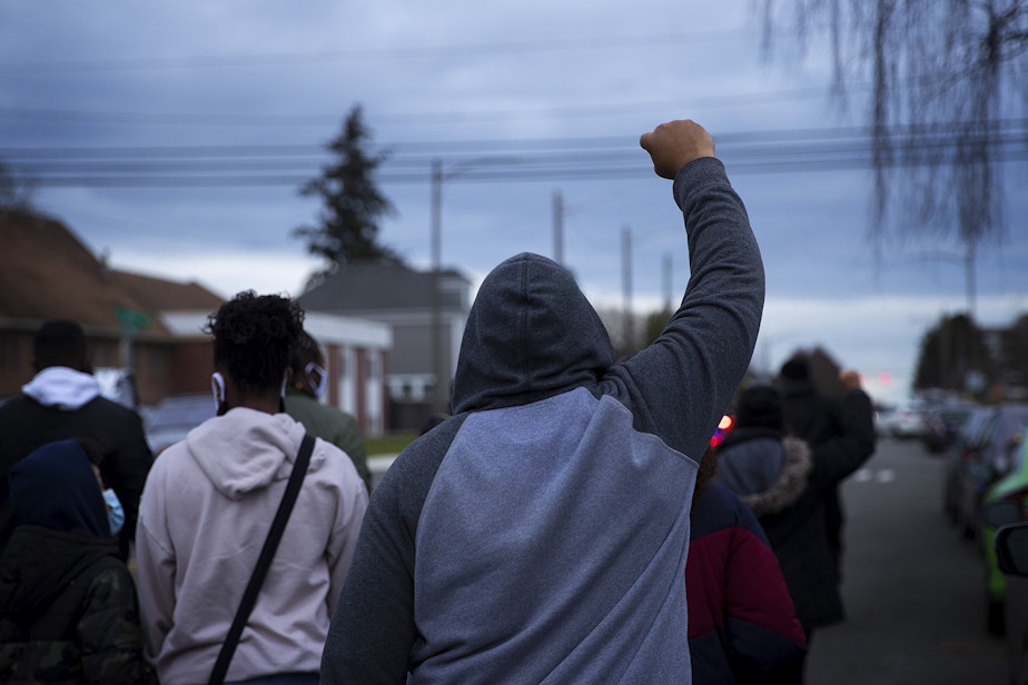 caption: A man raises his fist in the air while silently marching with about 200 others in honor of 33-year-old Manuel Ellis who was killed by Tacoma police officers after saying "I can't breathe, sir," one year ago, on Sunday, February 28, 2021, along Martin Luther King Jr. Way in Tacoma. 