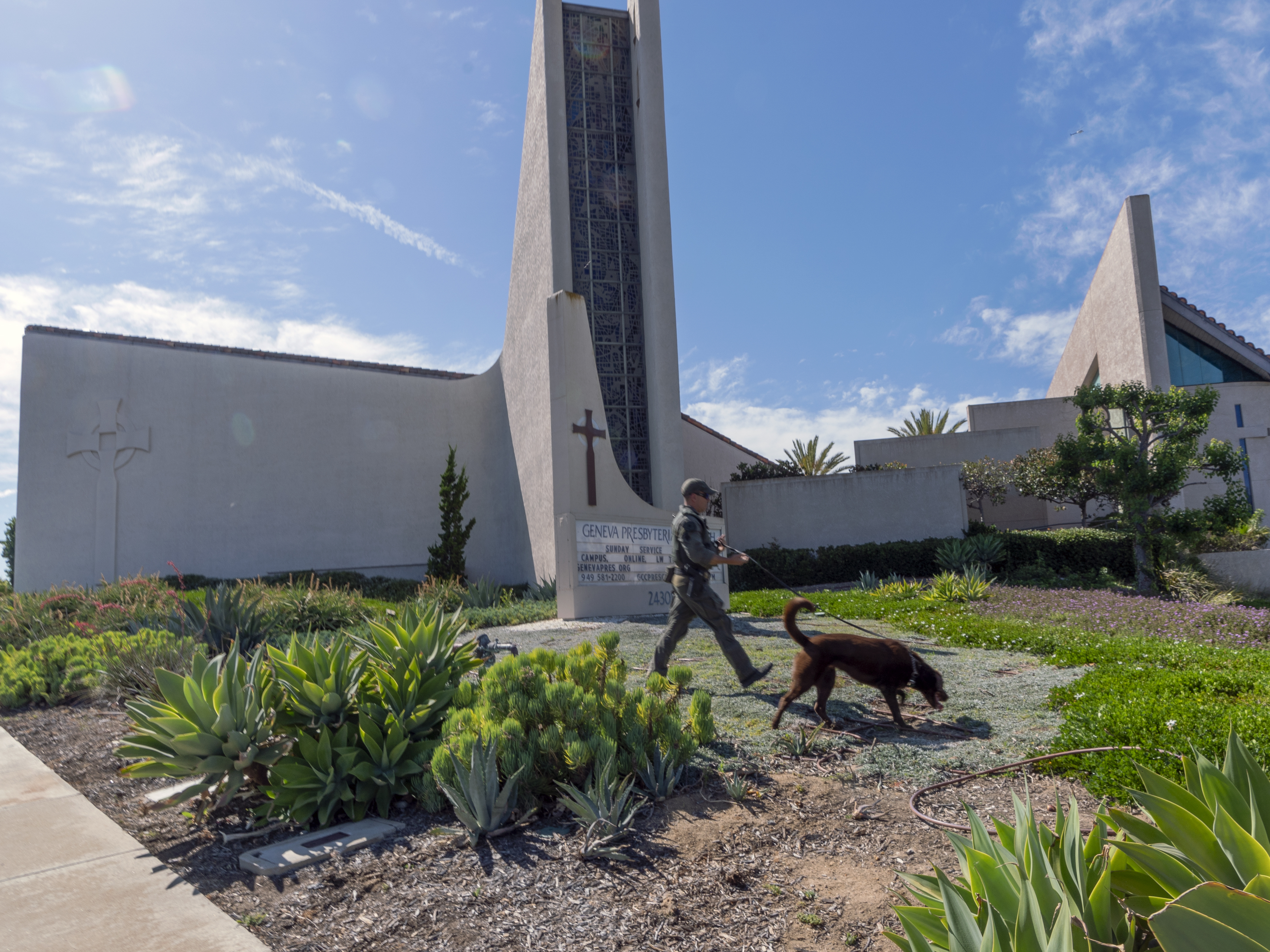 caption: An Orange County Sheriff's Department K-9 unit checks the grounds at Geneva Presbyterian Church in Laguna Woods, Calif. on Sunday after a fatal shooting.