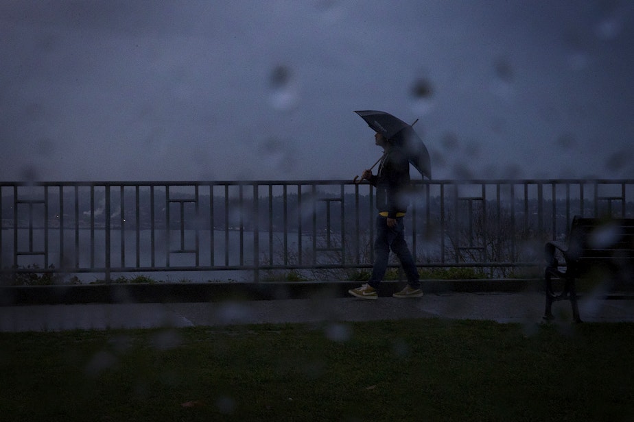 caption: A pedestrian walks through the rain in November 2019 at Kerry Park in Seattle.