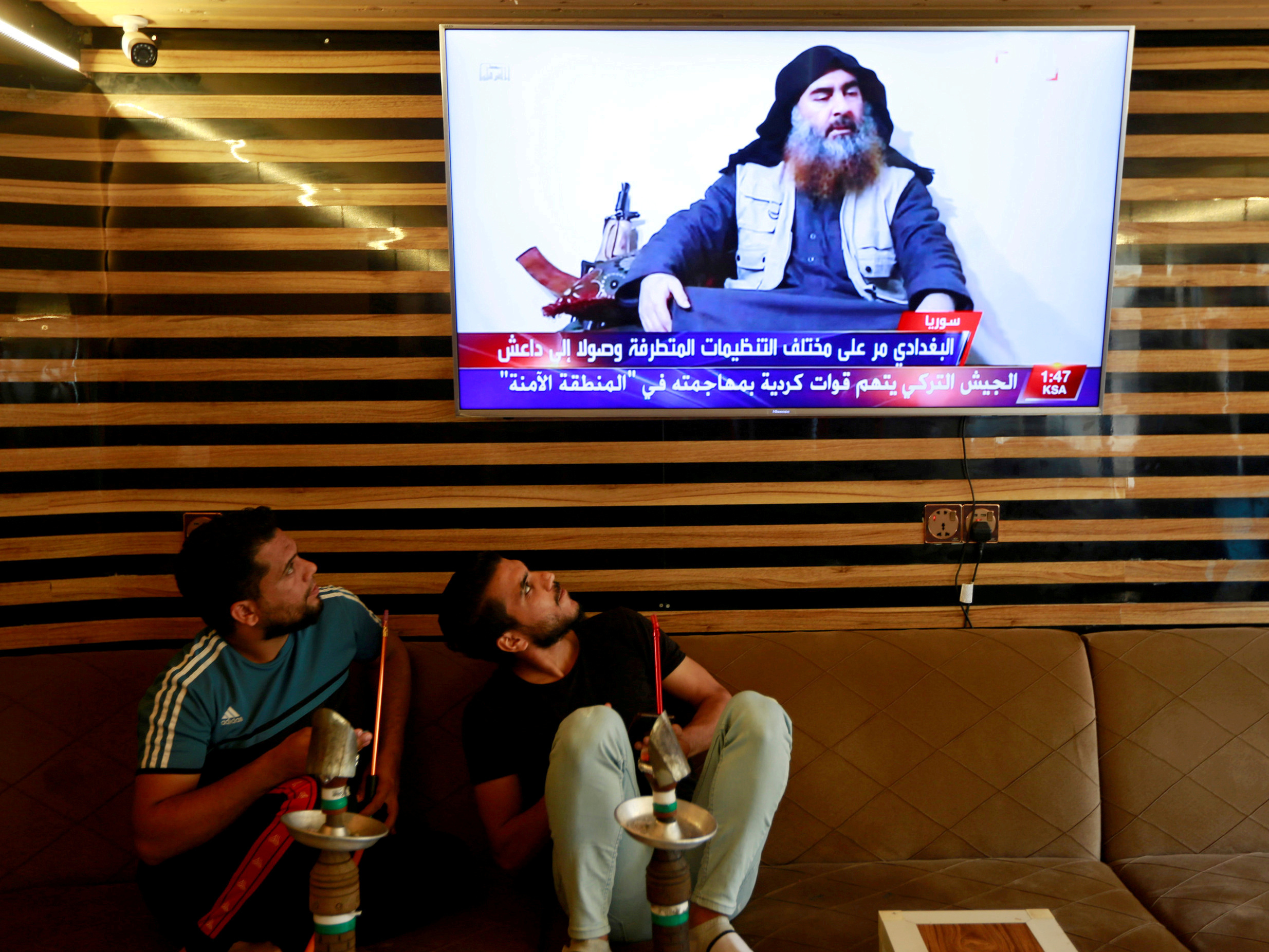 caption: Iraqi youth watch the news of ISIS leader Abu Bakr al-Baghdadi's death, in Najaf, Iraq, on Sunday.