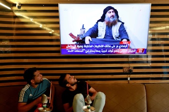 caption: Iraqi youth watch the news of ISIS leader Abu Bakr al-Baghdadi's death, in Najaf, Iraq, on Sunday.