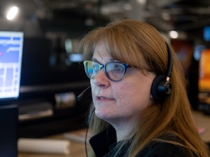 caption: Linda Anderson, an emergency communications technician, responds to a call at the Denver 911 dispatch center.
