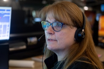 caption: Linda Anderson, an emergency communications technician, responds to a call at the Denver 911 dispatch center.