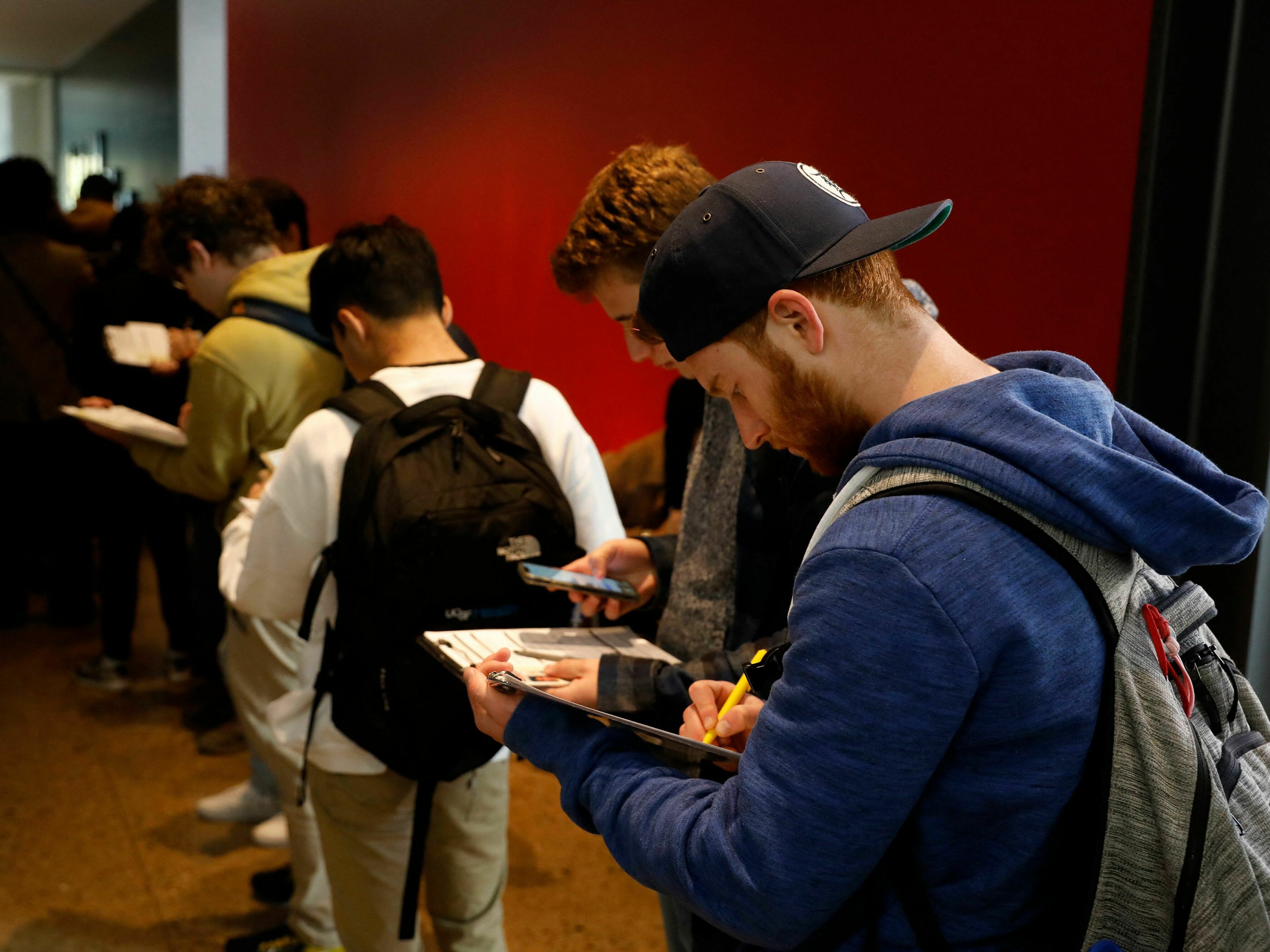 caption: A young man fills out an application to cast his ballot at the Ann Arbor clerk's satellite office on the University of Michigan campus.