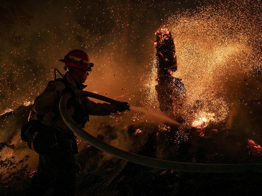 caption: Jason Marone cools down a hot spot burning close to homes last week in the Christmas Valley area of Meyers, Calif.