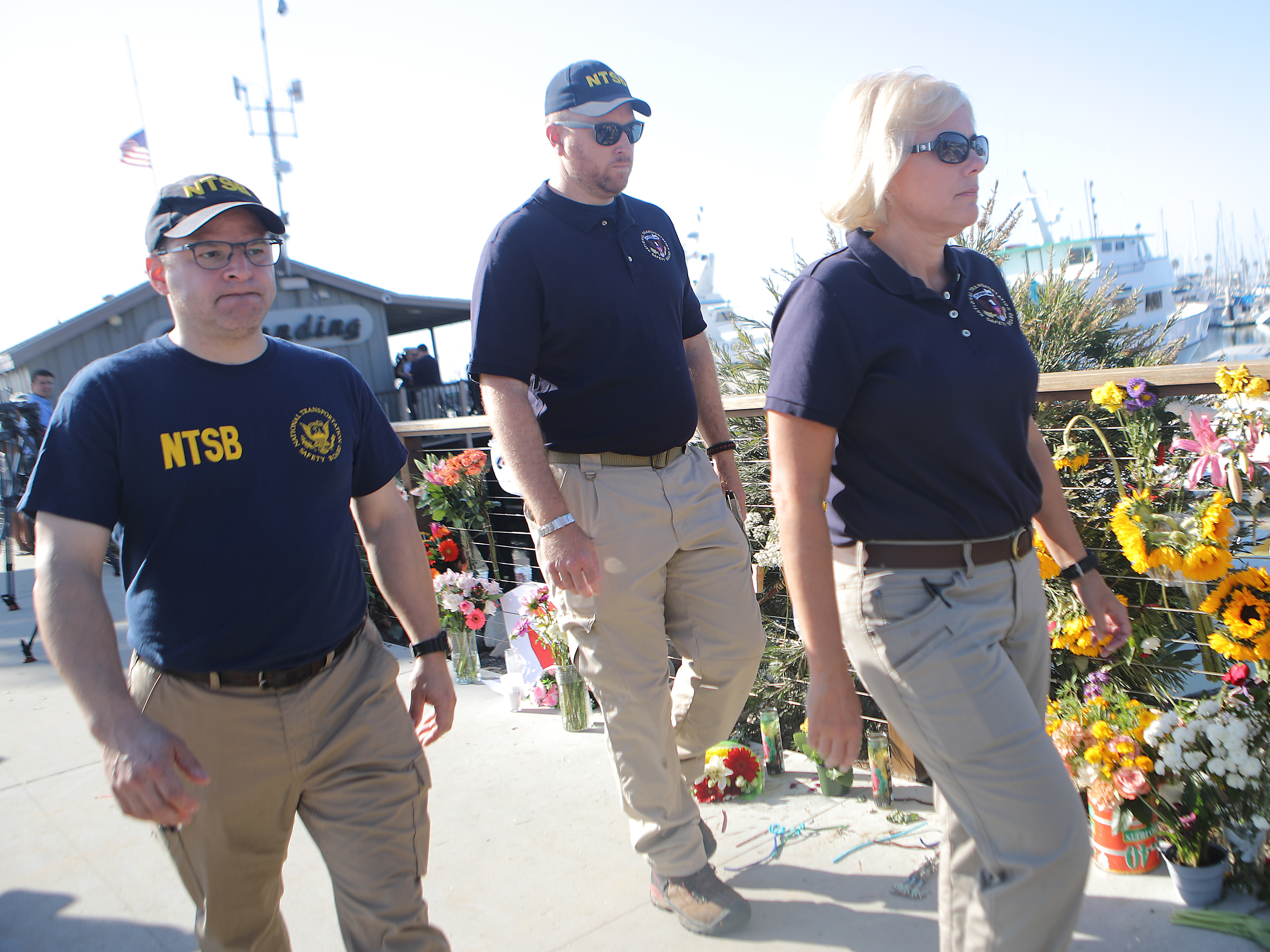 caption: National Transportation Safety Board member Jennifer Homendy (right) walks with other NTSB officials past a makeshift memorial for victims of the Conception boat fire in September 2019 in Santa Barbara, Calif.