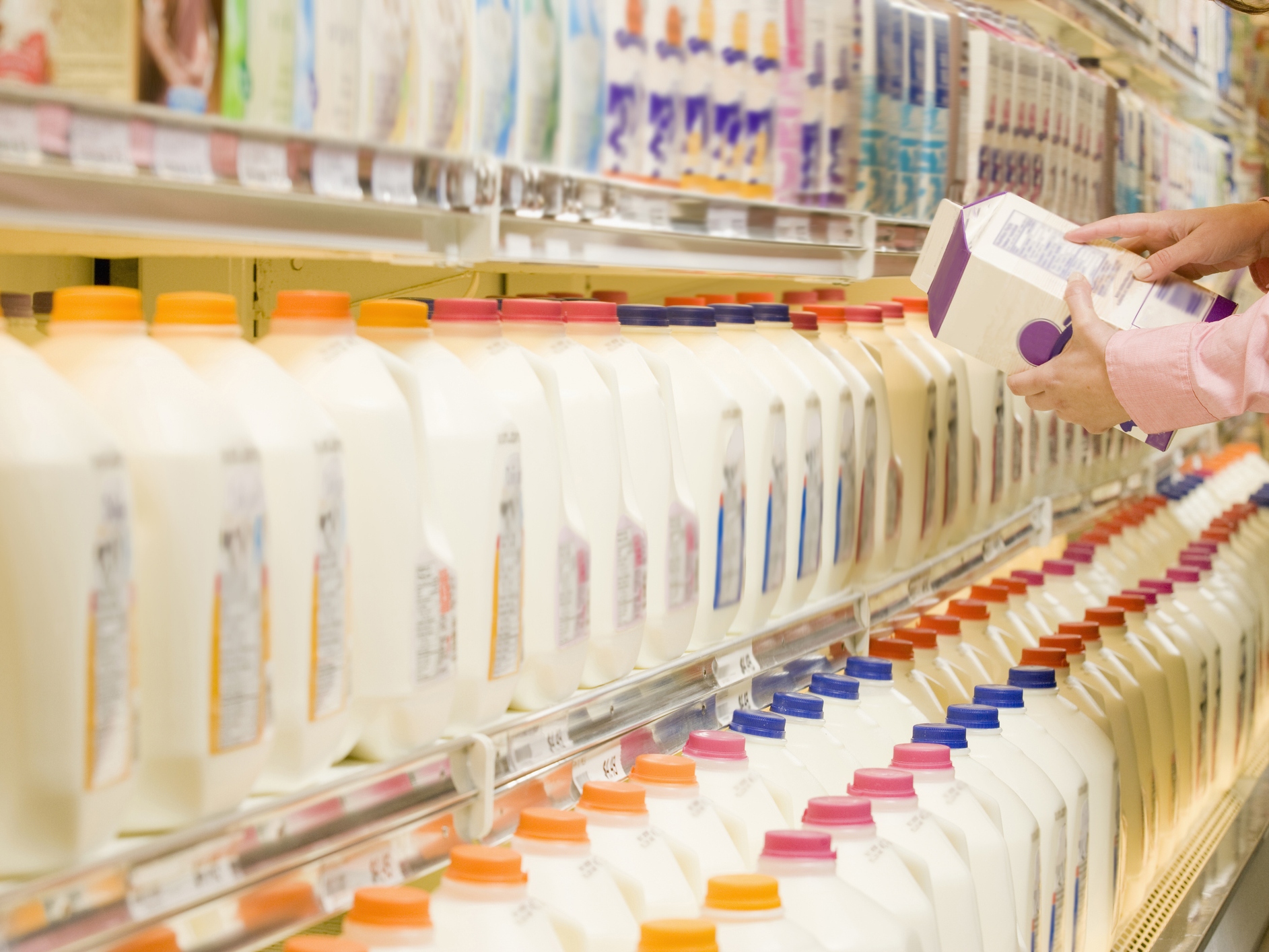 Woman checking ingredients on back of milk carton in supermarket