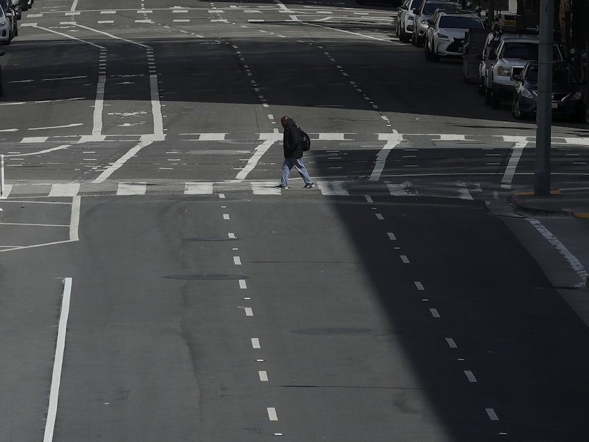 caption: A man crosses a nearly empty street in San Francisco, on March 17, 2020. Despite a reduction in driving last year, road fatalities increased, according to the National Safety Council.
