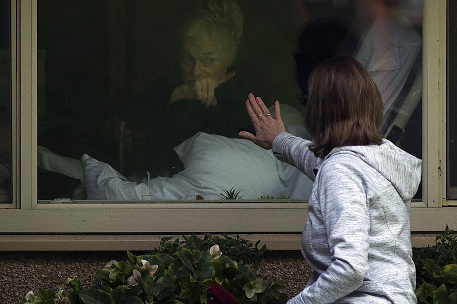 caption: Lori Spencer touches the glass of her mother Judie Shape's window while saying goodbye at the Life Care Center of Kirkland, the long-term care facility at the epicenter of the coronavirus outbreak in Washington state, on Wednesday, March 11, 2020, in Kirkland.