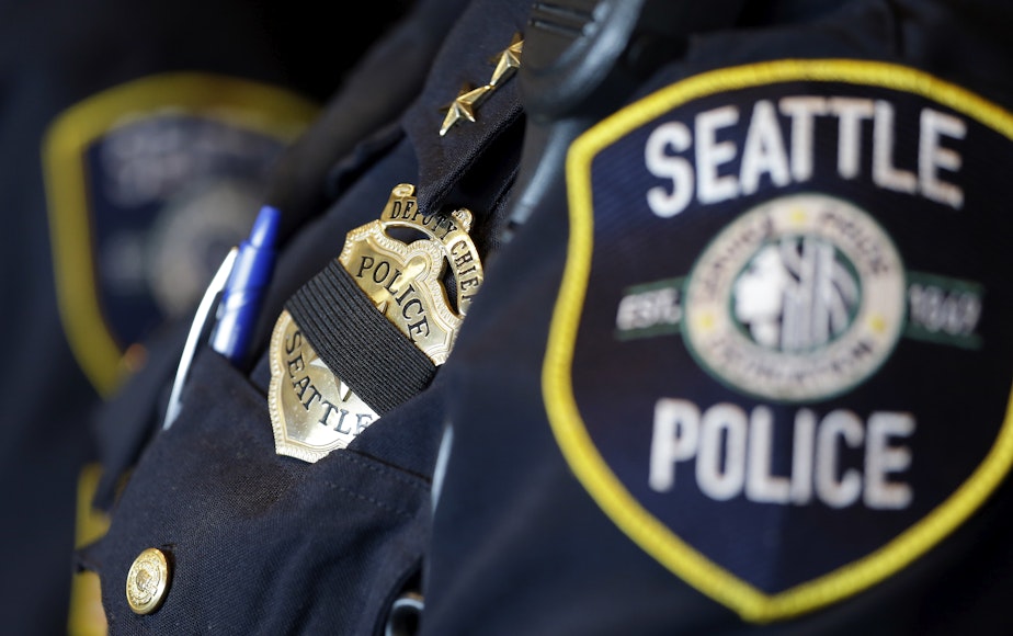 caption: FILE: A black band is drawn across the badge of Seattle Police Deputy Chief Carmen Best as she stands nearby during a news conference on Friday, July 8, 2016, in Seattle.