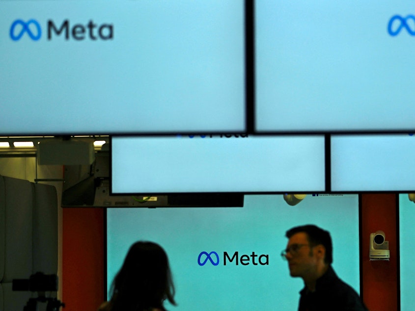 caption: Visitors stand near screens displaying the Meta logo in Berlin on June 6. Under a U.S. judge's new ruling, much of the federal government is now barred from working with social media companies to address removing content that might contain "protected free speech."