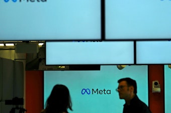 caption: Visitors stand near screens displaying the Meta logo in Berlin on June 6. Under a U.S. judge's new ruling, much of the federal government is now barred from working with social media companies to address removing content that might contain "protected free speech."