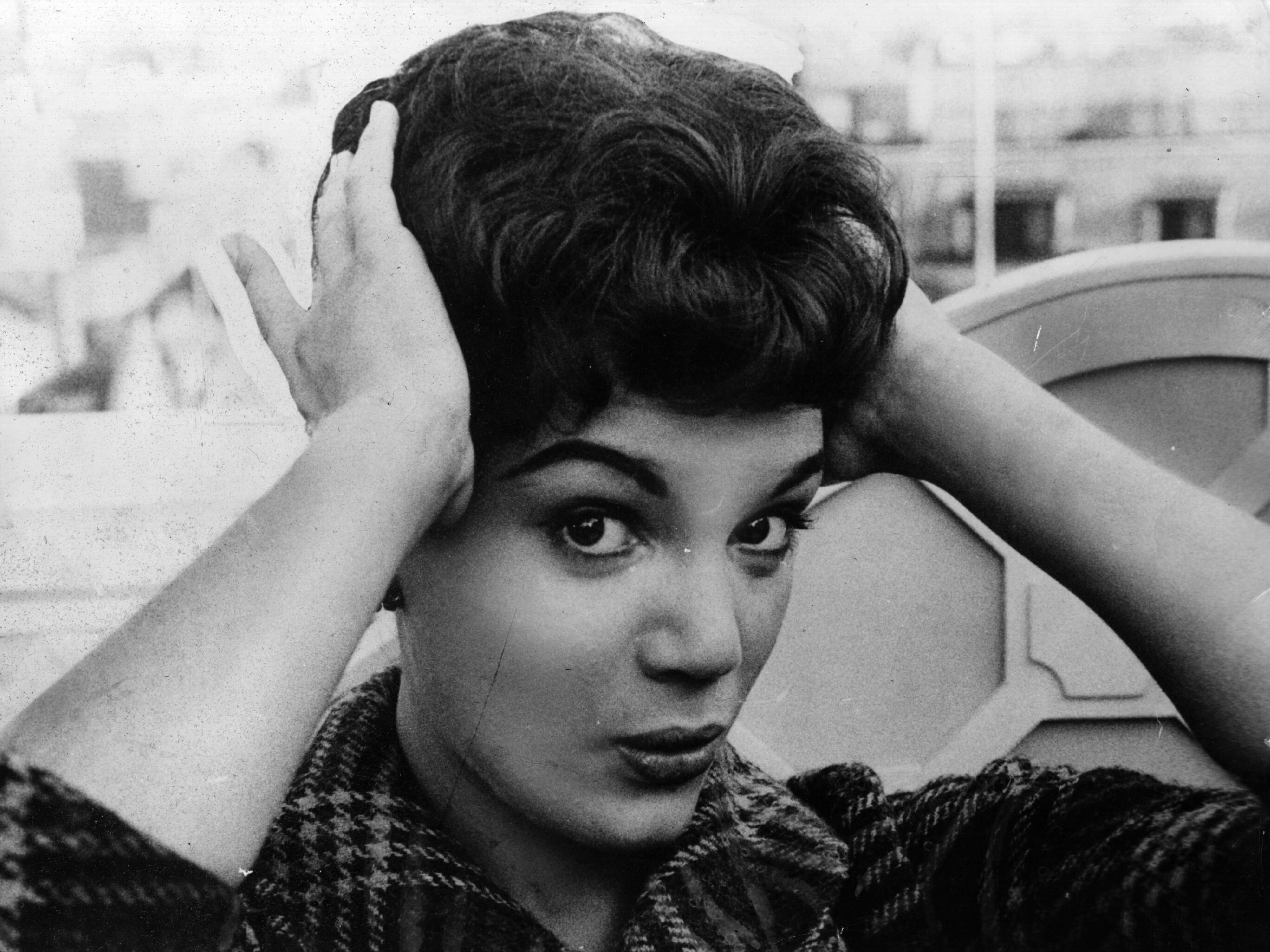 caption: Connie Francis fixes her hair during a 1959 press reception at the Dorchester Hotel in London