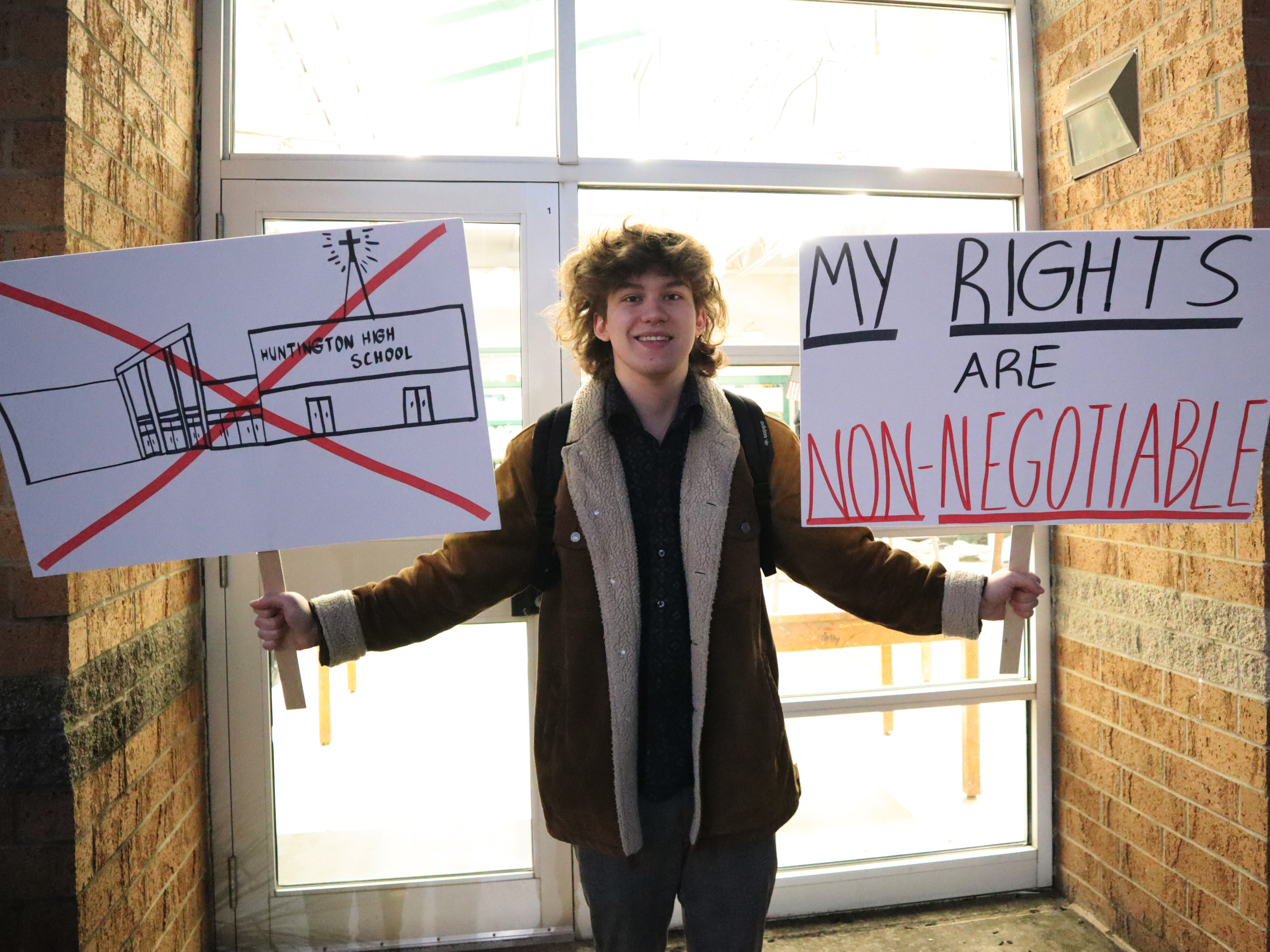 caption: Huntington High School senior Max Nibert holds signs he plans to use during a student walkout at the school in Huntington, W.Va., on Feb. 9. Now, families are suing the school district, alleging it violated students' religious freedoms.