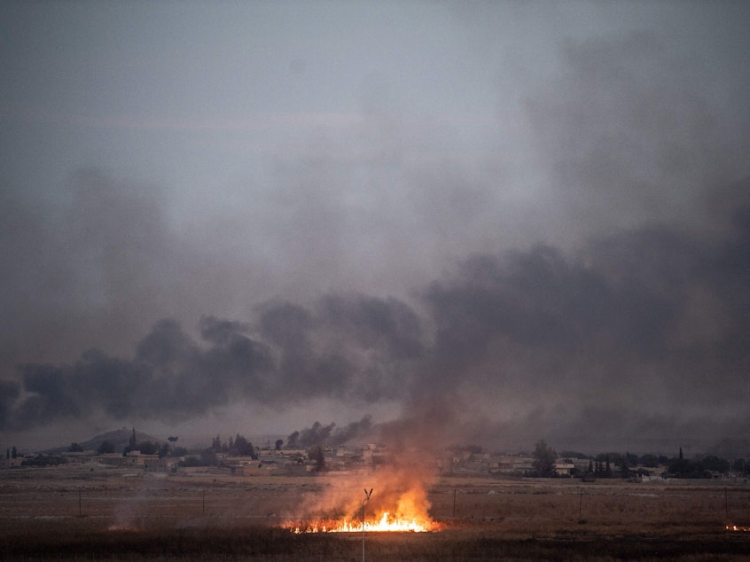 caption: Smoke rises from the Syrian town of Tal Abyad, where a hospital was shuttered because of the fighting. The photo was taken from the Turkish side of the border in Akcakale on October 10, the second day of Turkey's military operation against Kurdish forces.