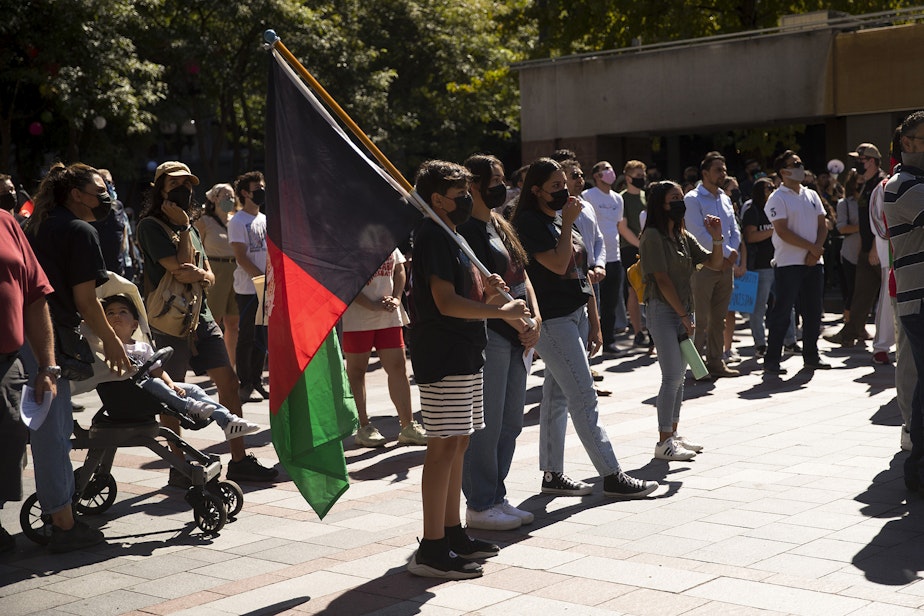 caption: Rehan Noori, 11, center, attends a rally and march with about 100 people standing in solidarity with Afghans on Saturday, August 28, 2021, at Westlake Park in Seattle.