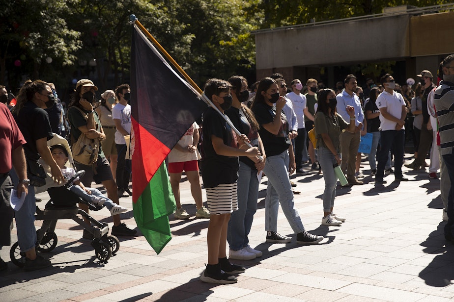 caption: Rehan Noori, 11, center, attends a rally and march with about 100 people standing in solidarity with Afghans on Saturday, August 28, 2021, at Westlake Park in Seattle. 